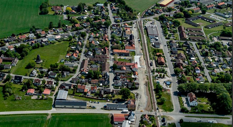 Flygfoto över Gärnsnäs där du kan se byns gator med villor, företagsbyggnader, järnvägen och omgivande fält och åkermark.