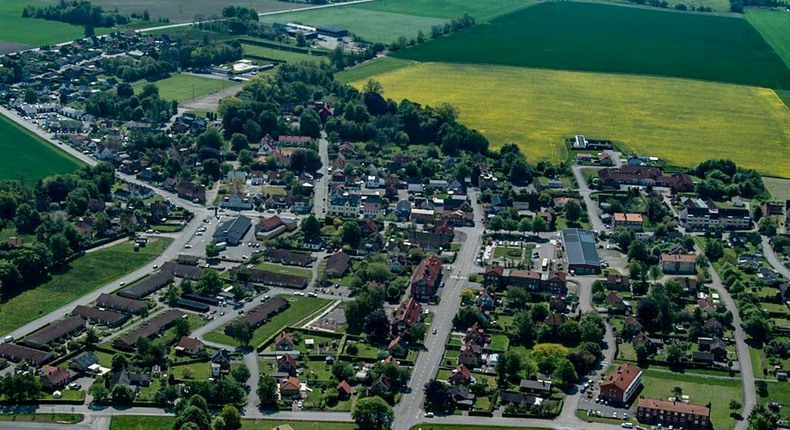 Flygfoto över Hammenhög med villor, flerbostadshus, verksamhetsbyggnader med vägar och träd, omgivna av rapsfält och åkermark.