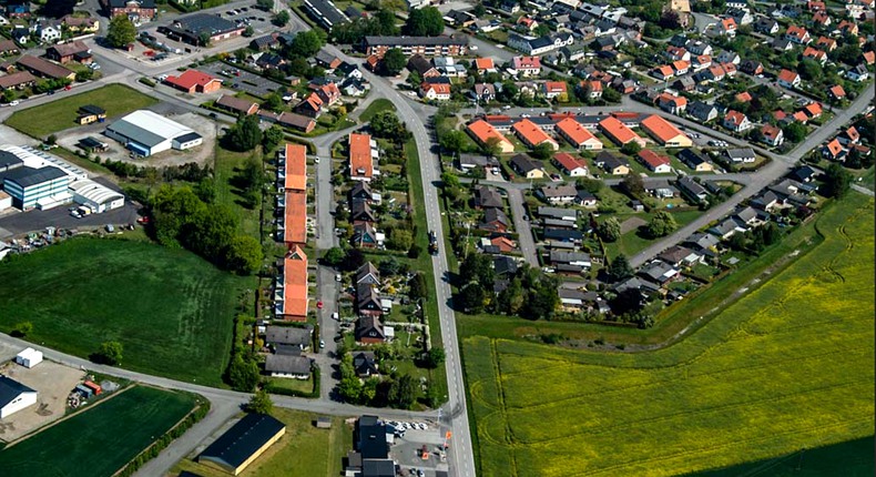 Flygfoto över Borrby. I nederkant raps och odlingsfält. Asfalterade vägar länkar samman bostadsområden. Här visas både industrilokaler, villor och flerbostadshus.