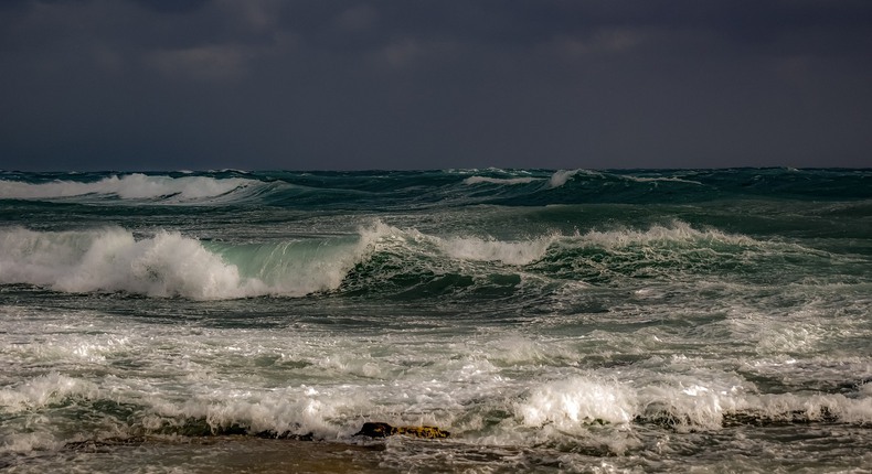 Bild på stormigt hav med stora vågor som rullar in över strand.