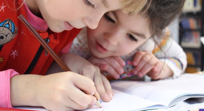 Två barn i förskoleklass skriver i en skrivbok. 