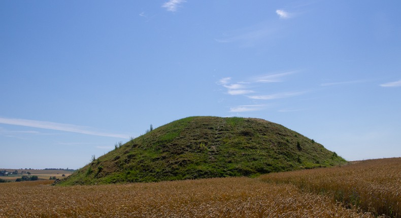 En grön kulle, Kvesahöj, reser sig mot en blå himmel från en åker.