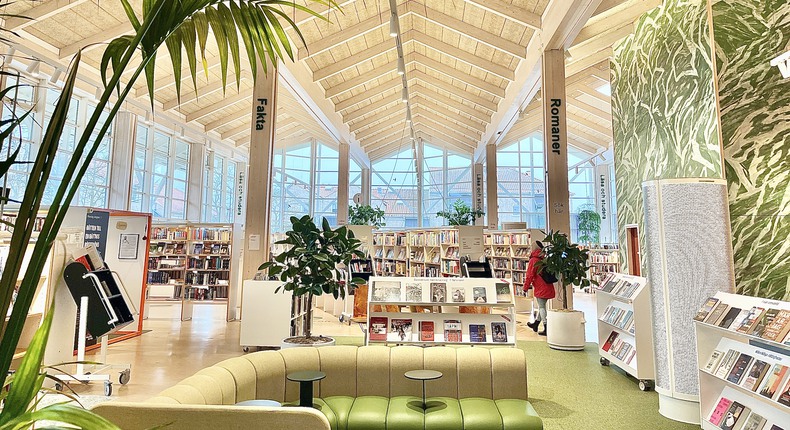 Interiör från Simrishamns bibliotek med sittgrupp, bokhyllor och gröna växter.